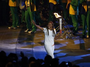 Charmaine Crooks carries the Pan Am flame during the opening ceremony of the 2015 Pan Am Games in Toronto, Friday, July 10, 2015.