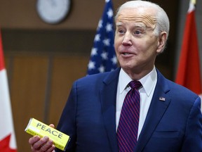 U.S. President Joe Biden reacts while holding a chocolate bar that was gifted to him on Parliament Hill in Ottawa, March 24, 2023