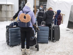A family of asylum seekers from Colombia is met by an RCMP officer after crossing the border at Roxham Road into Canada, Feb. 9, 2023 in Champlain, N.Y.
