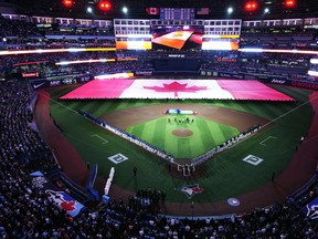 The Blue Jays and Detroit Tigers stand for the national anthem along with fans prior to the Blue Jays' home opener in Toronto on Tuesday, April 11, 2023.