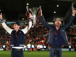 Rob McElhenney and Ryan Reynolds celebrate with the Vanarama National League trophy as Wrexham is promoted to the English Football on April 22, 2023 in Wrexham, Wales.