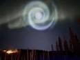 In this photo provided by Christopher Hayden, a light baby blue spiral resembling a galaxy appears amid the aurora for a few minutes in the Alaska skies near Fairbanks, Saturday, April 15, 2023. The spiral was formed when excess fuel that had been released from a SpaceX rocket that launched from California about three hours earlier turned to ice, and then the water vapour reflected the sunlight in the upper atmosphere.