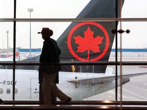 Travellers move between gates with an Air Canada plane in the background at the Calgary International Airport on Tuesday, Jan. 18, 2022.