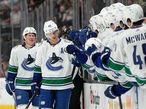 Vancouver Canucks center Elias Pettersson, second from left, celebrates his 100th point with teammates on the bench as he is followed by right wing Brock Boeser during the first period against the Anaheim Ducks on Tuesday, April 11, 2023, in Anaheim, Calif.