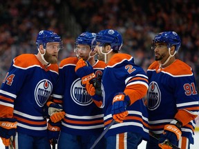 The Edmonton Oilers' Mattias Ekholm (14), Connor McDavid (97), Evan Bouchard (2) and Evander Kane (91) huddle during first-period NHL action against the Dallas Stars at Rogers Place in Edmonton, Thursday March 16, 2023.