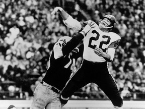 Joe Kapp (22) quarterback for the B.C. Lions manages to get his pass away before Pete Neumann (74) of the Hamilton Tiger Cats tackles him during the 1964 Grey Cup.