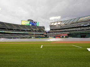 The grounds crew start to remove the tarp from the infield to prepare the field for play following a rain delay prior to the game between the Seattle Mariners and Oakland Athletics at RingCentral Coliseum on May 3, 2023 in Oakland, Calif.