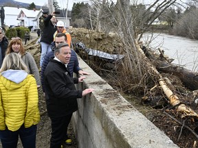 Quebec Premier François Legault watches the Rivière du Gouffre flow as he tours the site of a major spring flood, Wednesday, May 3, 2023, in Baie-St-Paul, Que.