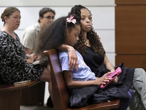 Philana Holmes and her daughter Olivia Caraballo, 7 listen to the final witness in their case at the Broward County Courthouse in Fort Lauderdale, Fla., on Wednesday May 10, 2023.