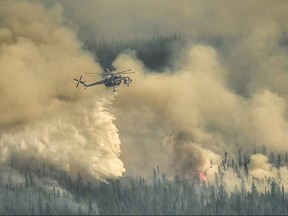 A Sky crane helicopter dumps water on the Eagle Wildfire Complex near Fox Creek, Alta., May 19, 2023.