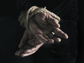 man with his hands tied behind his back