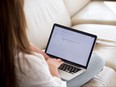 Rear view of woman writing email on laptop screen working from home.