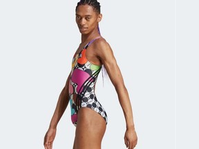 A women's one-piece Pride swimsuit is modeled by a male on the Adidas website.