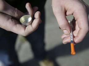 In this Oct. 22, 2018 file photo, a fentanyl user holds a needle near Kensington Ave. and East Cambria St. in Philadelphia