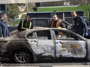 A police arson inspector looks over burned cars at a lot In Montreal, Que., Friday, Nov. 4, 2022.