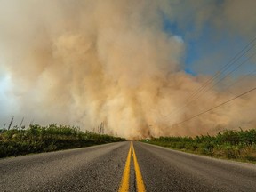 Smoke from a wildfire is shown crossing a road in British Columbia in this undated handout image provided by the BC Wildfire Service. A new out-of-control wildfire in British Columbia's Interior has sparked a mandatory evacuation order in area approximately 600 kilometres north of Vancouver.