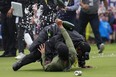 Canadian professional golfer Adam Hadwin, bottom, is stopped by a security guard while he tries to celebrates with Nick Taylor, of Canada, after Taylor won the Canadian Open championship on the fourth playoff hole on Sunday.