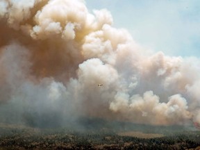 An aircraft (centre) disperses a mix of water and fire retardant over a fire near Barrington Lake in Shelburne County, N.S. in this Wednesday, May 31, 2023 handout photo.