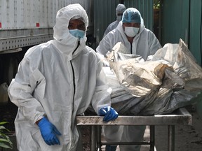 Forensic employees transport the corpses of several of the 46 dead women during a fire following a brawl between inmates of the Women's Social Adaptation Center (CEFAS) prison to the morgue to perform her autopsy in Tegicugalpa, on June 21, 2023.