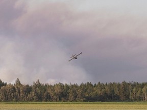 A water bomber flies toward a major field and forest fire in Quebec in 2020.