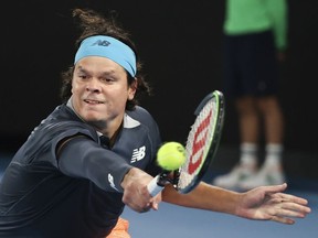 Canada's Milos Raonic hits a backhand return to Serbia's Novak Djokovic during their fourth round match at the Australian Open tennis championship in Melbourne, Australia, Sunday, Feb. 14, 2021.Raonic withdrew from the Cinch Championships on Tuesday shortly before his scheduled first-round match at the Wimbledon warm-up tournament.
