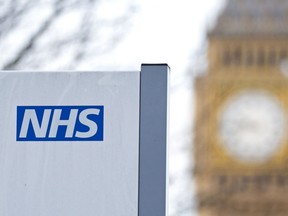 An NHS sign is pictured at St Thomas' Hospital in front of the Big Ben clock face and the Elizabeth Tower on January 13, 2017 in London.