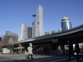 A resident crosses a quiet street near the Central Business District skyline in Beijing, Tuesday, Dec. 13, 2022.