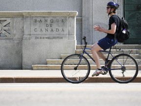 Economists are forecasting inflation fell closer to three per cent, the top end of the Bank of Canada's target range. A cyclist makes their way past the Bank of Canada in Ottawa on Tuesday, July 11, 2023.