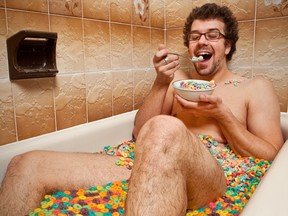 Man eating his cereal in the bathtub.