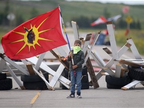 A young child carries a flag at a road block at Brady Road Landfill on Tuesday, July 11, 2023, as part of a protest against Manitoba Premier Heather Stefanson's decision to not search for murder victims.
