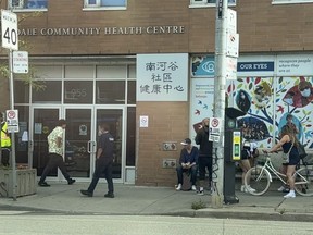 Locals and security outside the South Riverdale Community Health Centre on Queen St. East at Carlaw Ave. Jack Boland /Toronto Sun/Postmedia Network