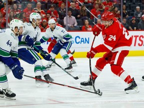 Detroit Red Wings center Pius Suter (24) shoots the puck against Vancouver Canucks defenseman Kyle Burroughs (44) in the second period at Little Caesars Arena. Rick Osentoski-USA TODAY Sports