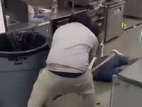 Screen shot of store owner beating thief with stick.