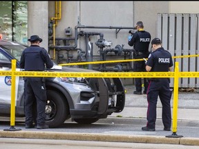 Toronto Police examine an alley at Bathurst St., between Lake Shore Blvd W. and Queens Quay W., in downtown Toronto on Friday, Aug. 11, 2023. It is believed that a man fell from a balcony and has since died, while another man was injured by the person who fell.