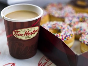 A cup of Tim Hortons Inc. coffee and doughnuts are arranged for a photograph in Toronto, Ontario, Canada, on Wednesday, Aug. 3, 2011.