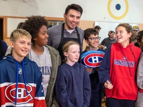 Canadiens captain Nick Suzuki poses for photos with students at Maple Grove Elementary School in Lachine on Monday.