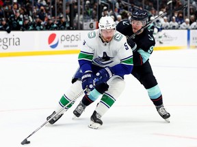 Tucker Poolman of the Vancouver Canucks skates against Ryan Donato of the Seattle Kraken during the second period at Climate Pledge Arena on Jan. 1, 2022 in Seattle.