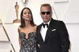 Christine Baumgartner and Kevin Costner arrive at the Oscars, March 27, 2022, at the Dolby Theatre in Los Angeles.