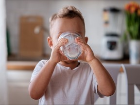 Little boy almost finished drinking glass of milk.
