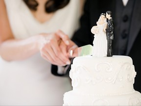 A newly married couple cut their wedding cake.