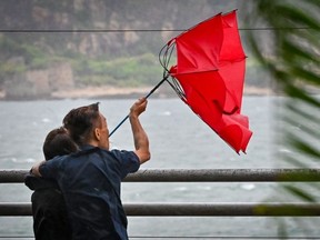 People struggle with their umbrella in high winds brought by Super Typhoon Saola in Heng Fa Chuen in Hong Kong on September 1, 2023. Super Typhoon Saola threatened southern China on September 1 with some of the strongest winds the region has endured, forcing the megacities of Hong Kong and Shenzhen to effectively shut down.