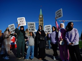 People hold signs during a demonstration on Parliament Hill in Ottawa on Wednesday, Sept. 20, 2023. Protests and counter-protests for and against Canada's trans and LGBTQ community are being planned across Canada on Wednesday.