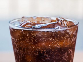 A glass of a cola drink with ice cubes.