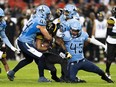 Tiger-Cats offensive linemen Tyreik McAllister (35) is tackled by Argonauts linebacker Trevor Hoyte (43) and linebacker Brandon Calver (44) during first half CFL action in Toronto, Saturday, Sept. 23, 2023.