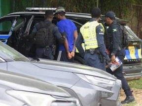 Suspected serial killer Ronaldo Ricketts, blue shirt, is taken into custody in Montego Bay.