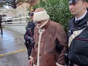 This handout video grab taken and released by the Italian Carabinieri Press Office on Jan. 16, 2023 shows the transfer of Italy's top wanted mafia boss, Matteo Messina Denaro (centre) from the Carabinieri police station of San Lorenzo in Palermo, to an undisclosed location, following his arrest in his native Sicily on Jan. 16, 2023 after 30 years on the run.