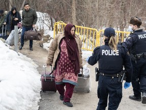 RCMP officers stop people as they enter Canada via Roxham road on the Canada/US border in Hemmingford, Que., Saturday, March 25, 2023.