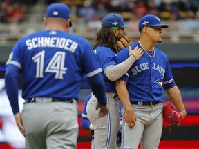 Toronto Blue Jays pitcher Jose Berrios, right, waits with shortstop Bo Bichette as manager John Schneider walks toward the mound to make a pitching change.