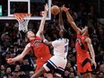 Naz Reid of the Minnesota Timberwolves is blocked at the net by Jakob Poelt and Scottie Barnes of the Toronto Raptors.