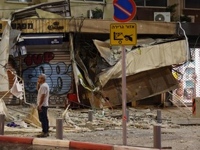 A man stands in front of a damaged shop in Tel Aviv, after it was hit by a rocket fired by Palestinian militants from the Gaza Strip on Oct. 7, 2023.